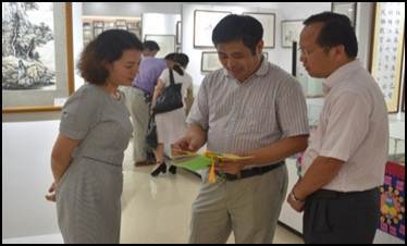 2018年9月13日，学校纪委书记覃宇环（左）和黄鹄副校长参观ok138cn太阳集团第一届师生书画展。